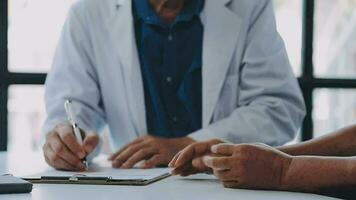 médecin et patient séance et parlant à médical examen à hôpital bureau, fermer. thérapeute remplissage en haut des médicaments histoire enregistrements. médicament et soins de santé concept. video