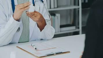 médecin et patient séance et parlant à médical examen à hôpital bureau, fermer. thérapeute remplissage en haut des médicaments histoire enregistrements. médicament et soins de santé concept. video