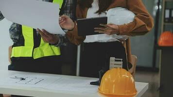 costruzione e struttura concetto di ingegnere o architetto incontro per progetto Lavorando con compagno e ingegneria utensili su modello edificio e planimetria nel Lavorando luogo, contrarre per tutti e due aziende. video