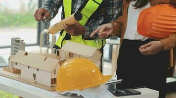 costruzione e struttura concetto di ingegnere o architetto incontro per progetto Lavorando con compagno e ingegneria utensili su modello edificio e planimetria nel Lavorando luogo, contrarre per tutti e due aziende. video