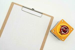 Blank clipboard paper and Emergency stop button isolated on white background. photo