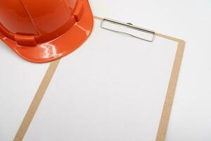 Blank clipboard paper and hard hat or safety helmet isolated on white background. photo