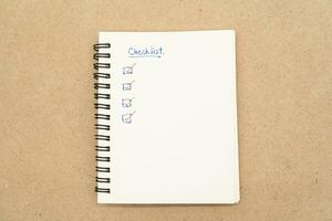 Top view of notebook with handwritten Checklist text. Checklist concept, checklist box with red checkmark. photo