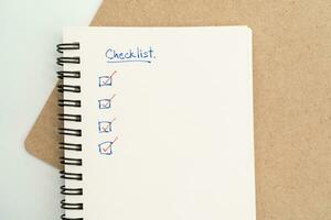 Top view of notebook with handwritten Checklist text. Checklist concept, checklist box with red checkmark. photo