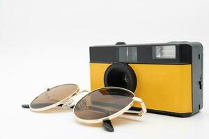 Film camera or Vintage camera with Sunglasses . Minimal hipster summer trend. Retro design camera on isolated background. Summertime concept. Travel, Holiday, Vacation in summer concept. photo