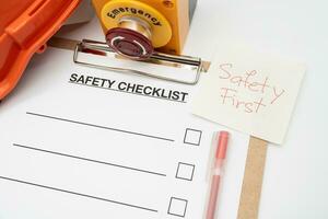 Safety First Text Note. Blank checklist paper during safety audit and risk verification. safety checklist form with Hard hat or Safety hat and Emergency Stop Button. photo