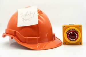 Orange safety hat with message Safety First and Emergency Stop Button isolated on white background. Safety First Concept. photo