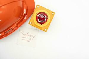 Orange safety hat with message Safety First and Emergency Stop Button isolated on white background. Safety First Concept. photo