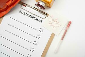 Safety First Text Note. Blank checklist paper during safety audit and risk verification. safety checklist form with Hard hat or Safety hat and Emergency Stop Button. photo