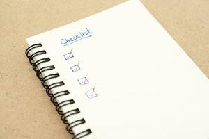 Top view of notebook with handwritten Checklist text. Checklist concept, checklist box with red checkmark. photo