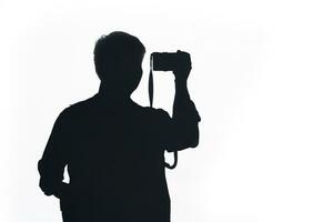 Silhouette man pose using camera. Silhouette man takes photo with camera isolated on white background.