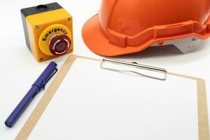 Blank clipboard paper, Emergency stop button, Pen and hard hat or safety helmet isolated on white background. photo