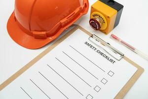 Blank checklist paper during safety audit and risk verification. safety checklist form with Hard hat or Safety hat and Emergency Stop Button. photo