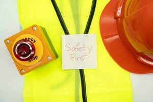 Safety First message on paper. Safety Gear. Reflective vest, safety hat or helmet and Emergency Stop Button. Safety First Concept. photo