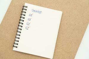 Top view of notebook with handwritten Checklist text. Checklist concept, checklist box with red checkmark. photo