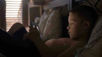 kind aan het liegen in bed en aan het kijken tekenfilm Aan tablet computer video