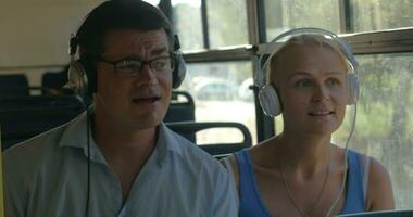 jovem casal ouvindo para música em fones de ouvido durante a ônibus andar de, elas dança para a música, homem cantando video