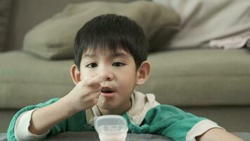 A boy happily uses a spoon to scoop up yogurt. video