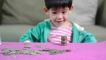 Asian boy arranging coins in a row to practice saving money video