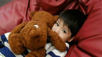 A boy is sleeping and hugging a teddy bear on a red mattress. video