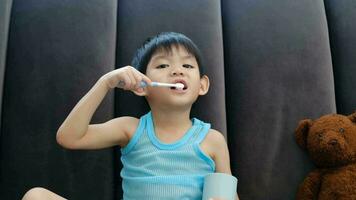 Asian boy brushing his teeth on the living room video