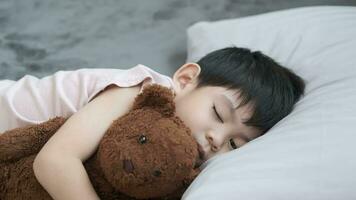 A boy is sleeping and hugging a teddy bear in bed. video