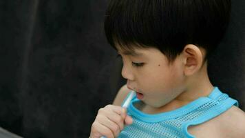 Asian boy brushing his teeth on the living room video