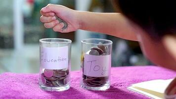 Male Asian boy holding a silver coin Choose to save money between toys or studying. video