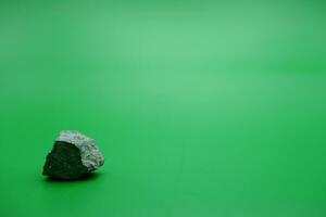 a small stone isolated green background. stone used for building materials. photo