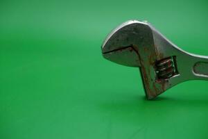 a wrench on a green background. wrench that has started to rust. photo