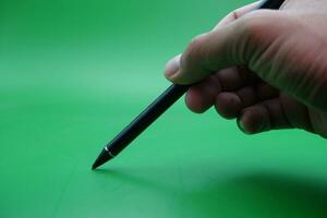 a black stylus pen being held over a green background. photo