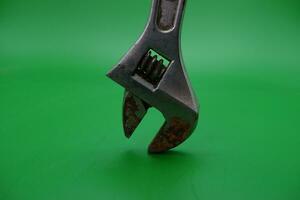 a wrench on a green background. wrench that has started to rust. photo