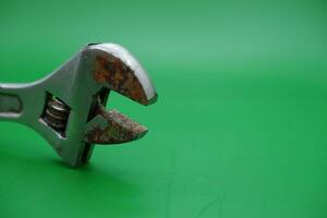 a wrench on a green background. wrench that has started to rust. photo