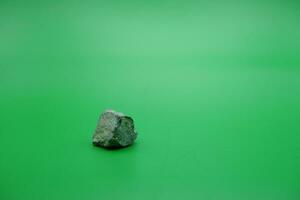 un pequeño Roca aislado verde antecedentes. Roca usado para edificio materiales foto
