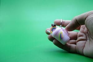 hand holding a cute key chain on a green background photo