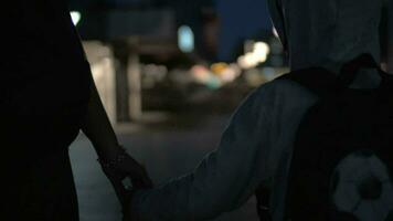 Child and mother holding hands while walking at night video