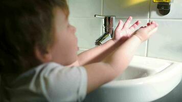 Boy washing hands with soft soap and turning off water video