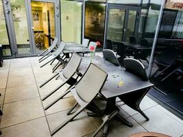 mesa y sillas en un al aire libre patio después el lluvia. allí son No personas en el acogedor bar. foto