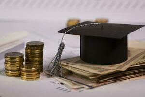 graduation cap and money on a desk photo