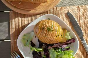 Baked jacket potatoes with dip, mixed green salad leaves and hemp oil photo