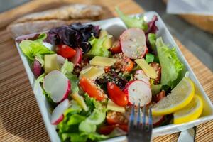 a white square bowl with salad photo