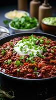 Spicy chili con carne topped with sour cream and chives photo