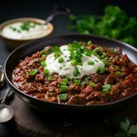 Spicy chili con carne topped with sour cream and chives photo