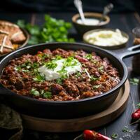 Spicy chili con carne topped with sour cream and chives photo