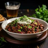 Spicy chili con carne topped with sour cream and chives photo