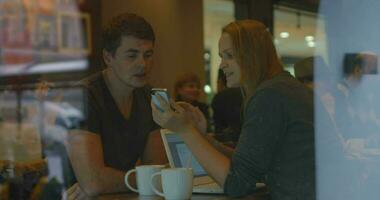junge Leute, die Smartphone benutzen und im Café sprechen video
