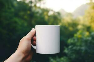 Hand holding a white mug on the background of a mountain landscape. photo