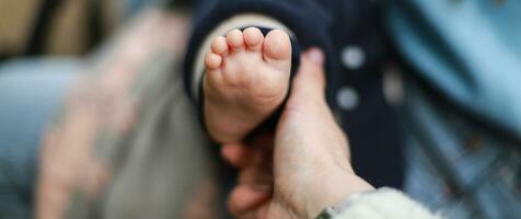 Banner Little baby foot. The hand holds the child is leg. Children Protection Day photo