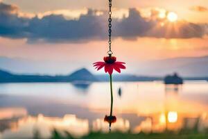 a red flower hanging from a chain by a lake. AI-Generated photo