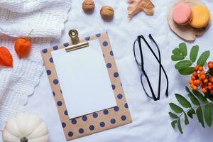 Blank sheet of paper, eyeglasses and autumn cozy decor top view, flat lay. Copy space for autumn text photo